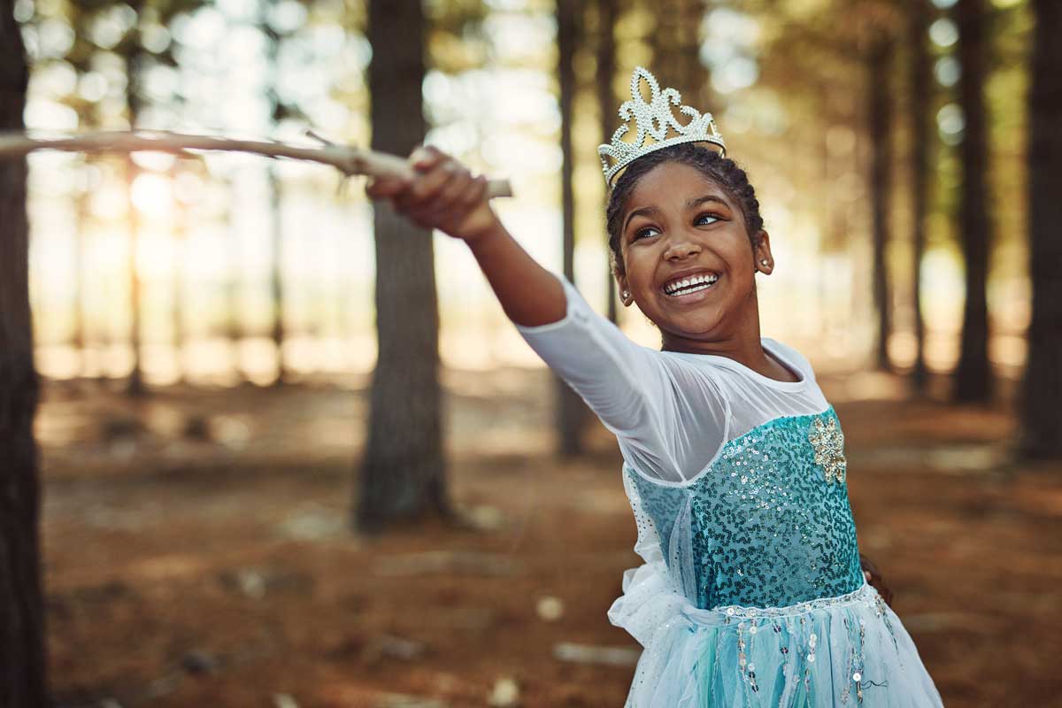 Aufnahme eines kleinen Mädchens, das als Prinzessin verkleidet ist und im Wald spielt