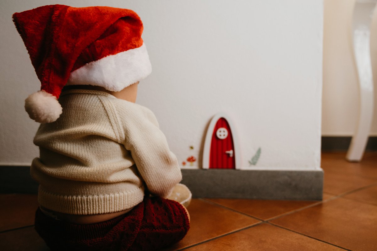 Kleinkind sitzt erwartungsvoll vor der Tür des Weihnachtswichtels.